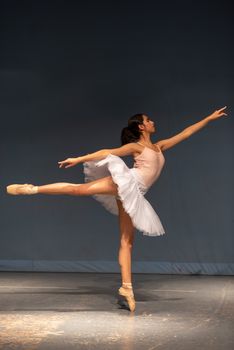 A graceful ballerina performing a stunning pose on stage during a ballet rehearsal.