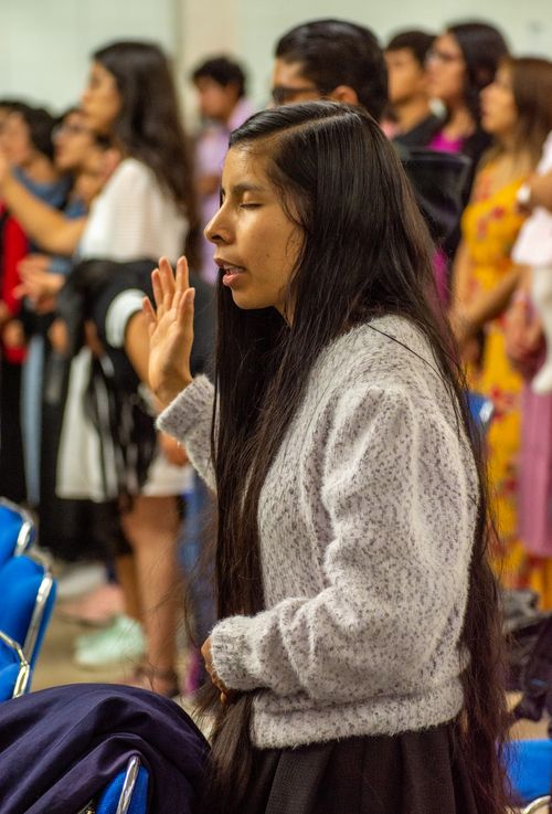 Free A woman with long hair prays with others in a communal indoor gathering. Stock Photo