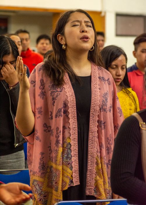 Free Young woman in traditional attire praying with eyes closed at an indoor event. Stock Photo