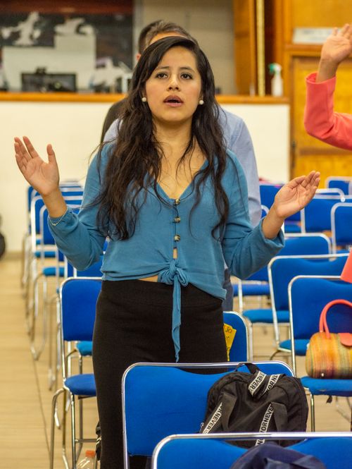 Free A woman with long hair stands with raised hands during an indoor religious event. Stock Photo