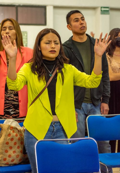 Free Group of people worshiping indoors, raising hands in a religious gathering. Stock Photo