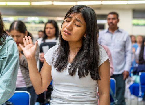 Free A young woman with closed eyes prays during a worship service in a community setting. Stock Photo