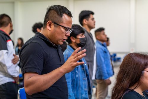 Free A focused group of adults standing and praying in a bright indoor setting. Stock Photo