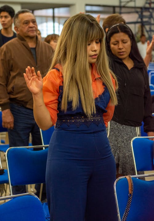 Blonde Woman Praying with Hand Raised