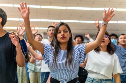 Free Diverse young adults engaging in a worship session with raised hands. Stock Photo