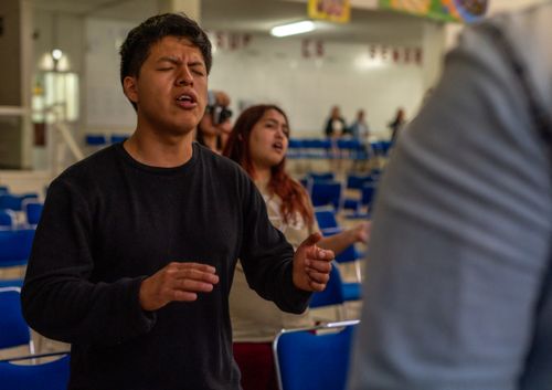 Free Young people engaged in a worship session indoors, expressing devotion and community spirit. Stock Photo