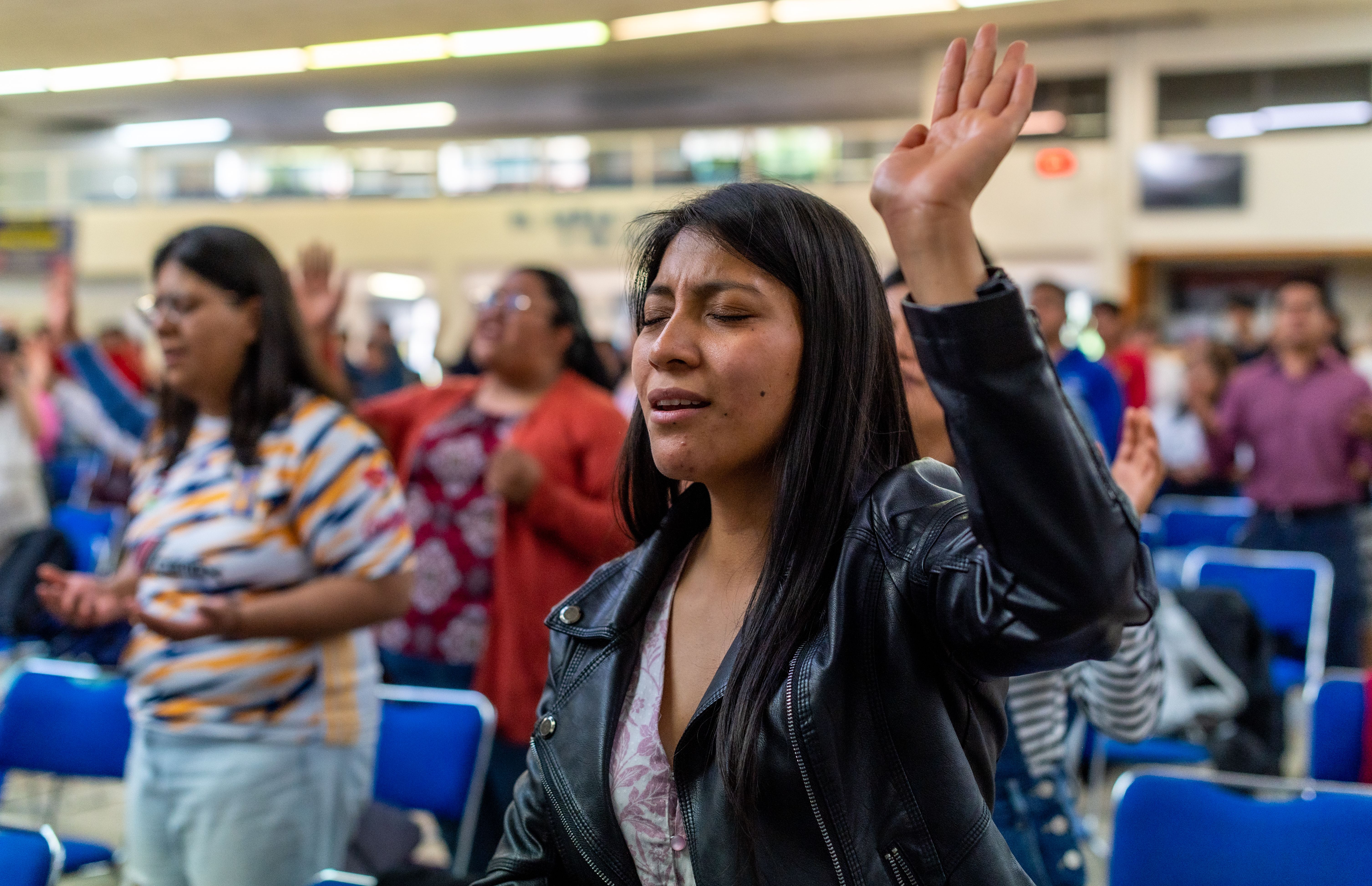 Close-up of a Christ Embassy Loveworld Arena service with people raising hands and smiling