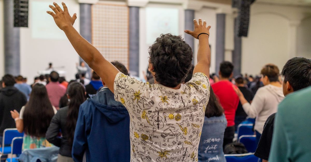 crowd of worshippers with hands raised in a large church arena in Ghana