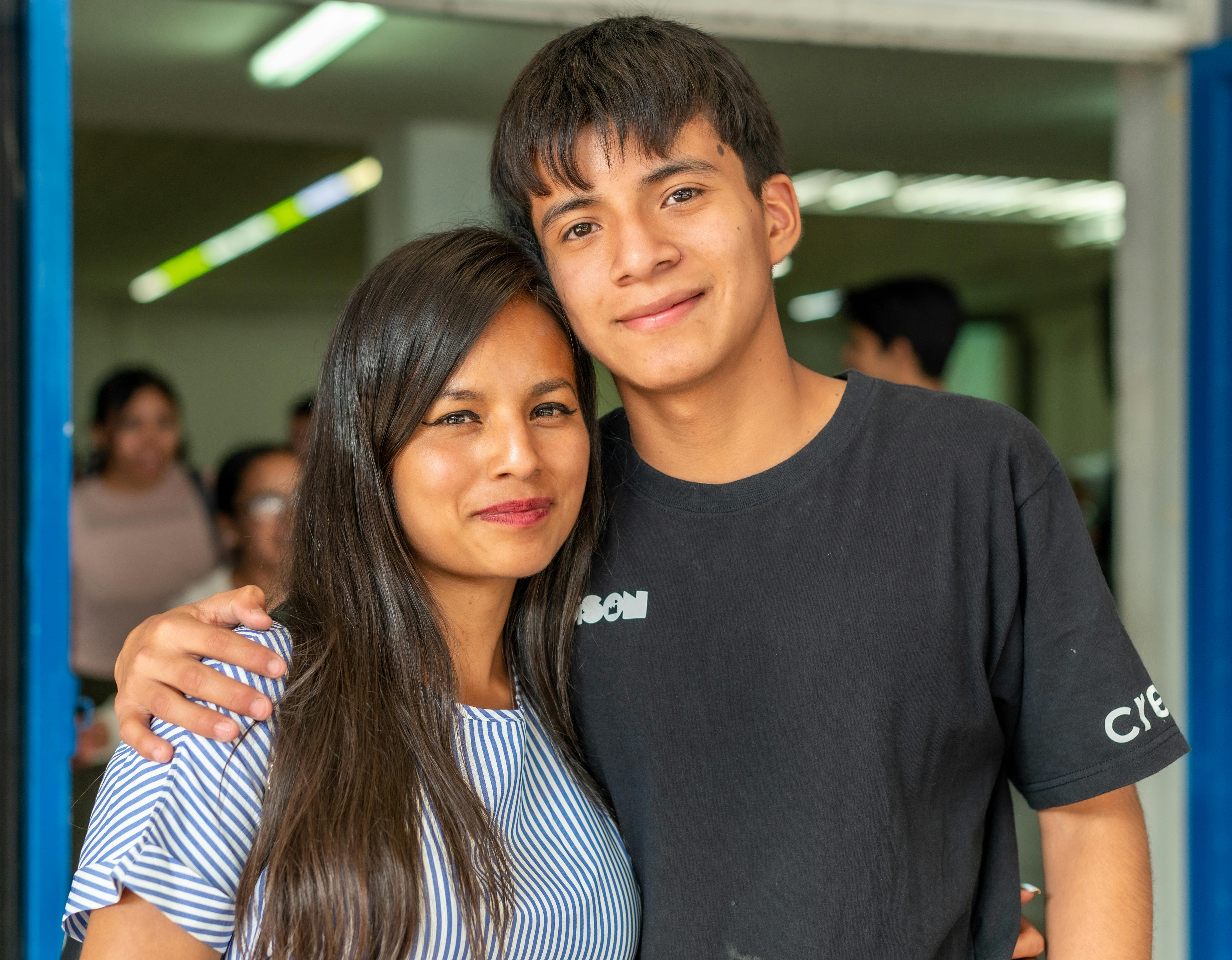 a young man and woman standing together in front of a building