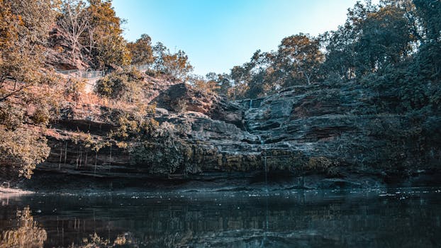 平静的湖水中倒映着岩石悬崖的宁静景色，四周环绕着郁郁葱葱的森林