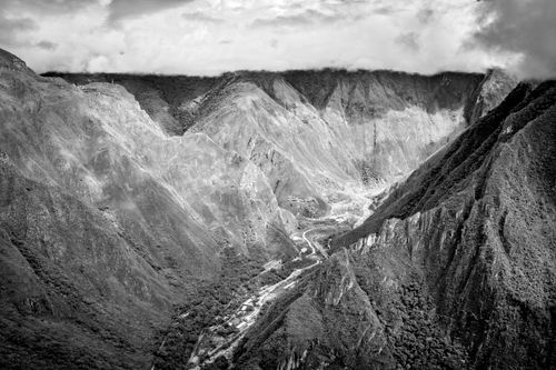Free A stunning black and white aerial view of a rugged mountain valley landscape with cloud cover. Stock Photo
