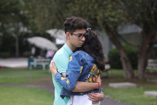 A young couple shares a heartfelt embrace in a lush park setting, expressing intimacy and connection.