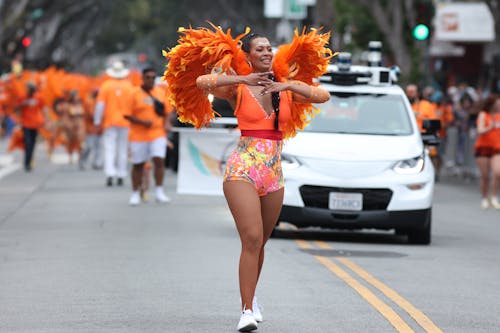 Woman in a Costume Walking on a Street with a Crowd behind Her at a Parade 