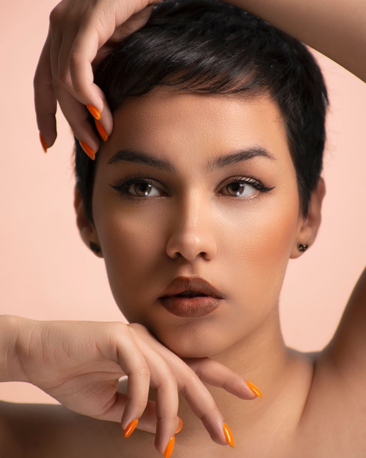 Close-up portrait of a woman posing with vibrant nail color and short black hair.