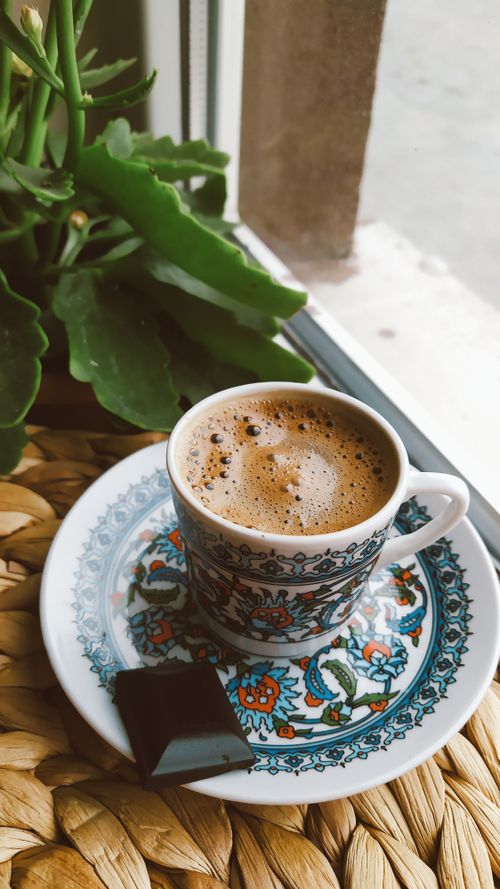 Free Artistic coffee cup with rich espresso and chocolate by a window setting. Stock Photo