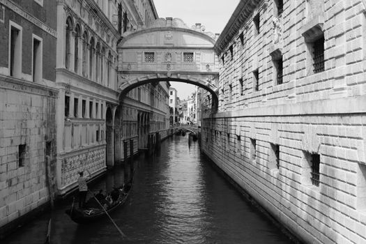 A gondola rides under the historic Bridge of Sighs in Venice, Italy, capturing the city's architectural charm.