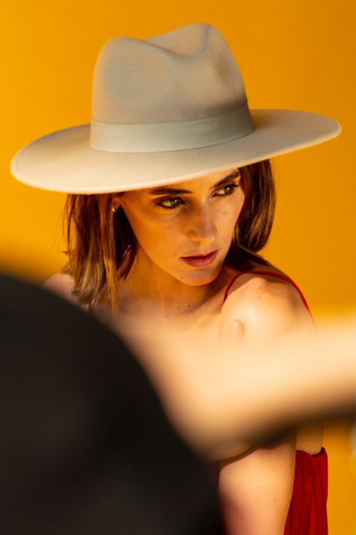 Free Portrait of a fashionable woman posing elegantly in a neutral hat against a yellow backdrop. Stock Photo
