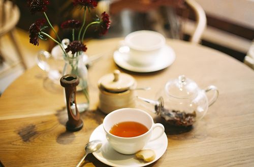 Free Elegant table setup with a cup of tea, cookie, and flowers, providing a cozy atmosphere. Stock Photo