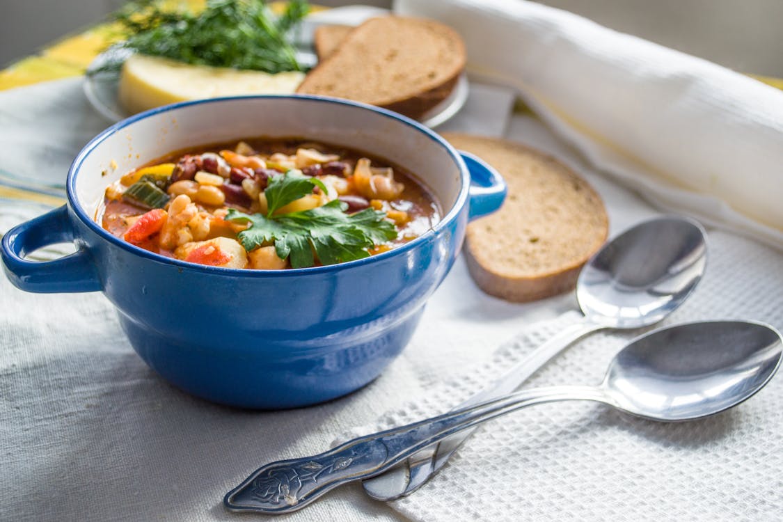 Free Bowl Of Soup And Two Silver Spoons Stock Photo