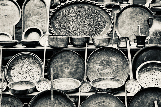 Collection of vintage metal dishes and containers displayed in a market, showcasing intricate designs.