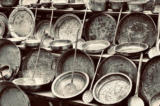 A collection of vintage metal kitchenware including pots and ladles with intricate patterns.
