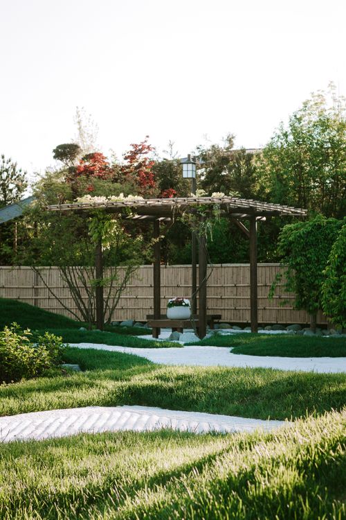 Free Peaceful garden arbor with lush greenery and sunlight in a tranquil park setting. Stock Photo
