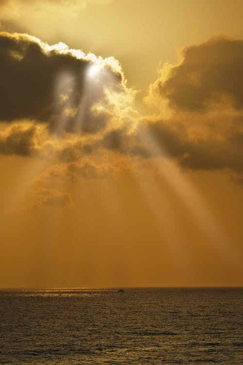 The Sun Shining from behind the Clouds onto the Sea 
