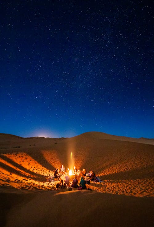 Люди, сидящие перед костром в пустыне в ночное время