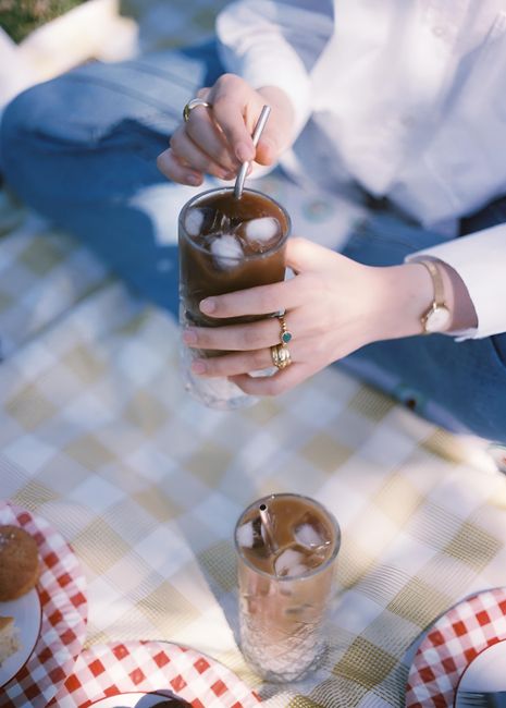 Enjoy a sunny picnic in Istanbul with refreshing iced coffee and snacks on a checkered blanket.