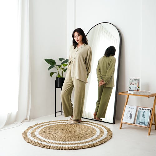Young Model in a Green Blouse and Pants Set in Front of the Mirror