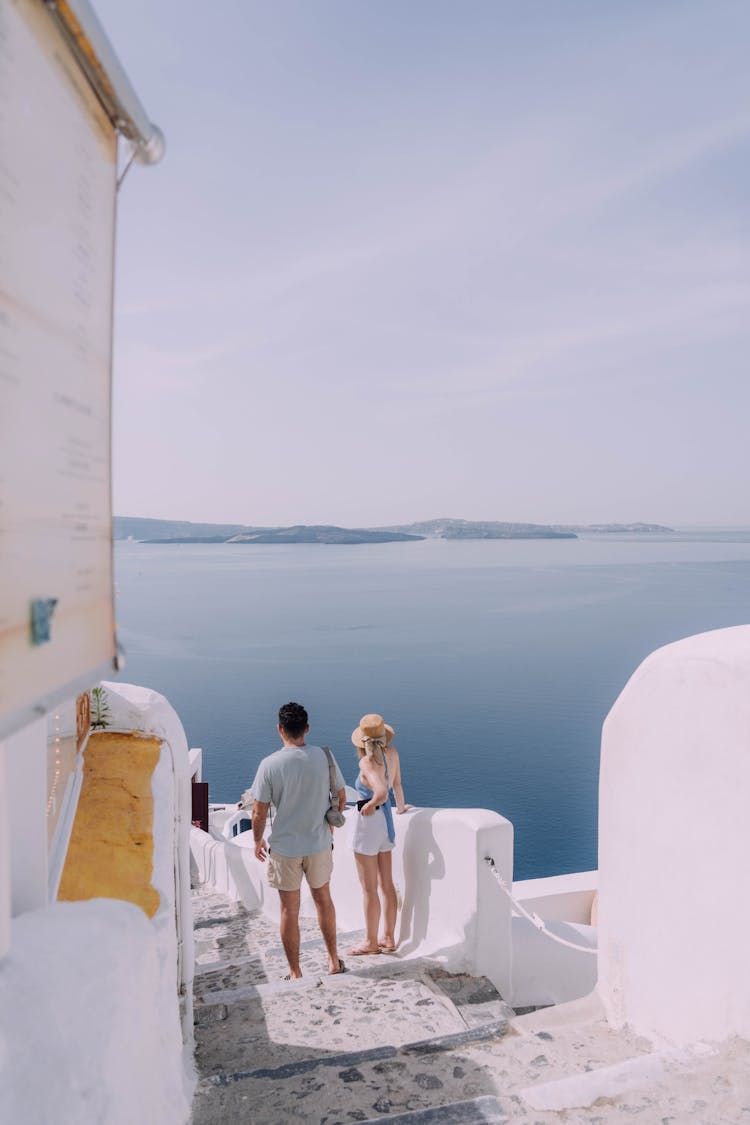 Couple Walking Down The Stairs In Santorini, Greece