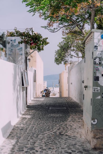 A picturesque cobblestone alley with white buildings in Santorini, Greece.