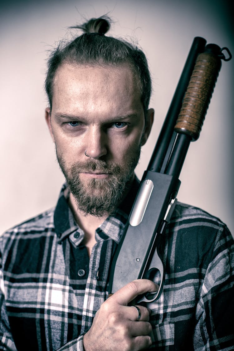 Man In Checked Shirt Posing With Weapon