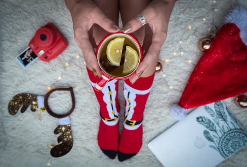 Нарезанный цитрус внутри кружки в окружении праздничных рождественских костюмов