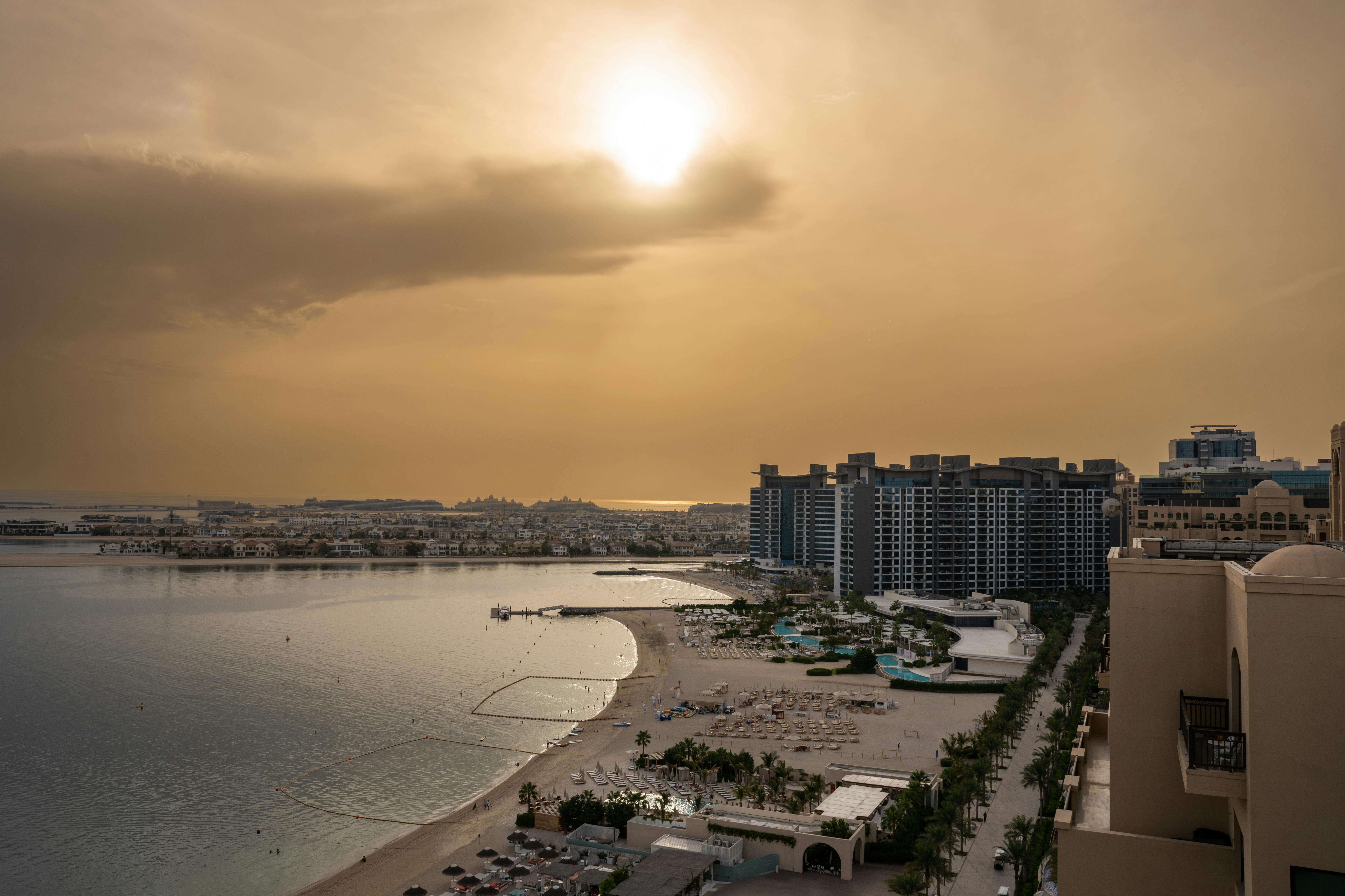A captivating view of urban beachfront with dramatic sunset sky and luxury resort buildings.