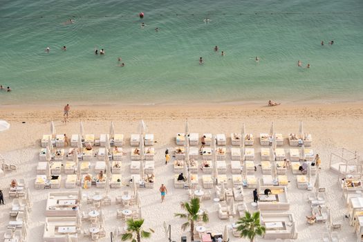 Aerial view of a luxurious beach resort with sun loungers and people enjoying the ocean.