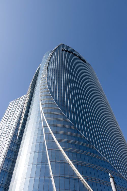 Free Low angle view of modern skyscraper facade with blue sky backdrop. Stock Photo
