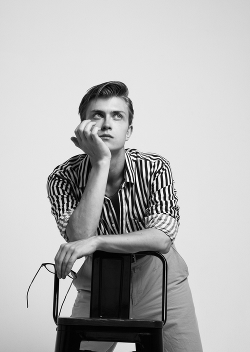 Free Black and white portrait of a young male model in a striped shirt, posing thoughtfully. Stock Photo