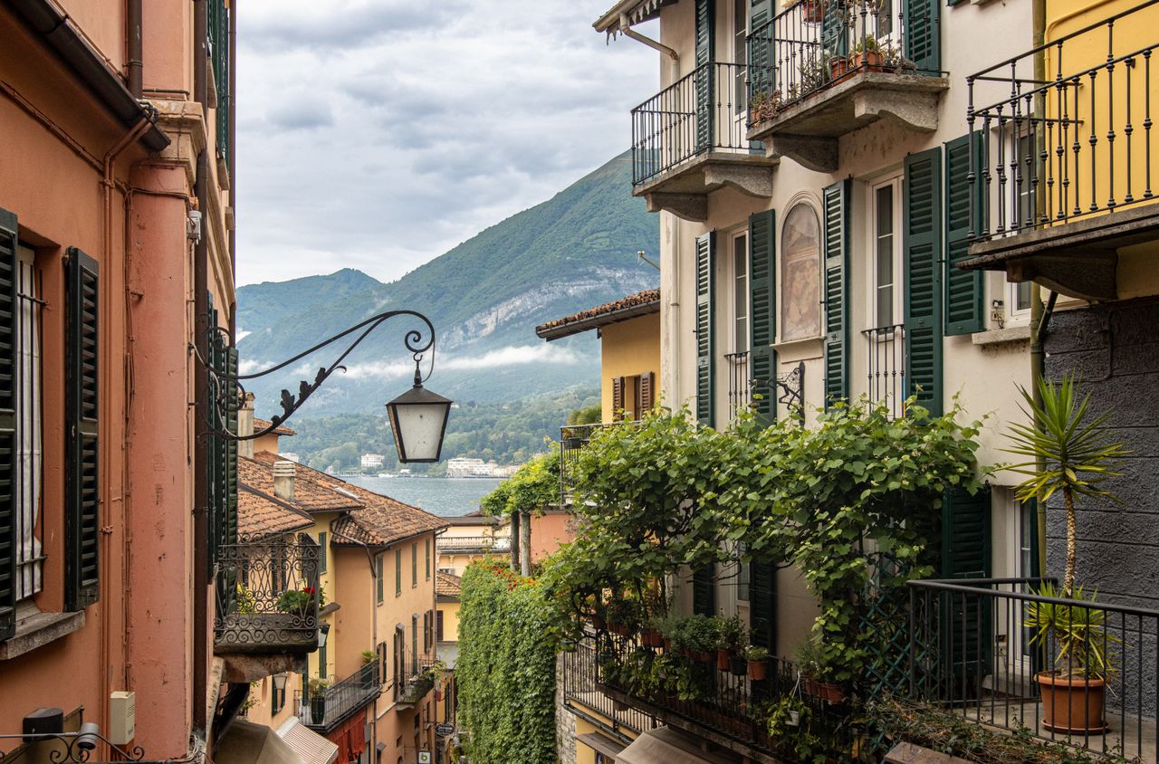 picturesque italian street with ornate balconies and a mountain in the