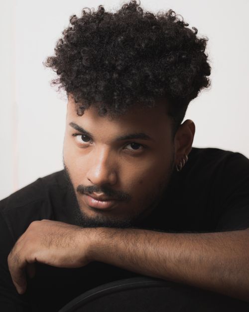 Free Intimate studio portrait of a man with curly hair and earrings in Pão de Açúcar, Brazil. Stock Photo