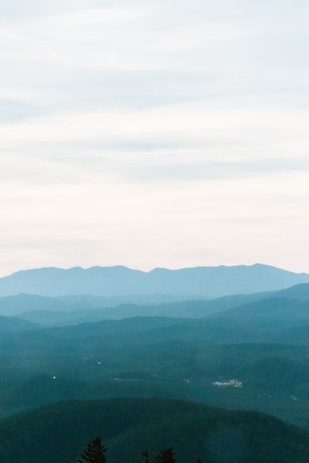 Explore the tranquil beauty of a misty mountain range with layered hills under a serene sky.