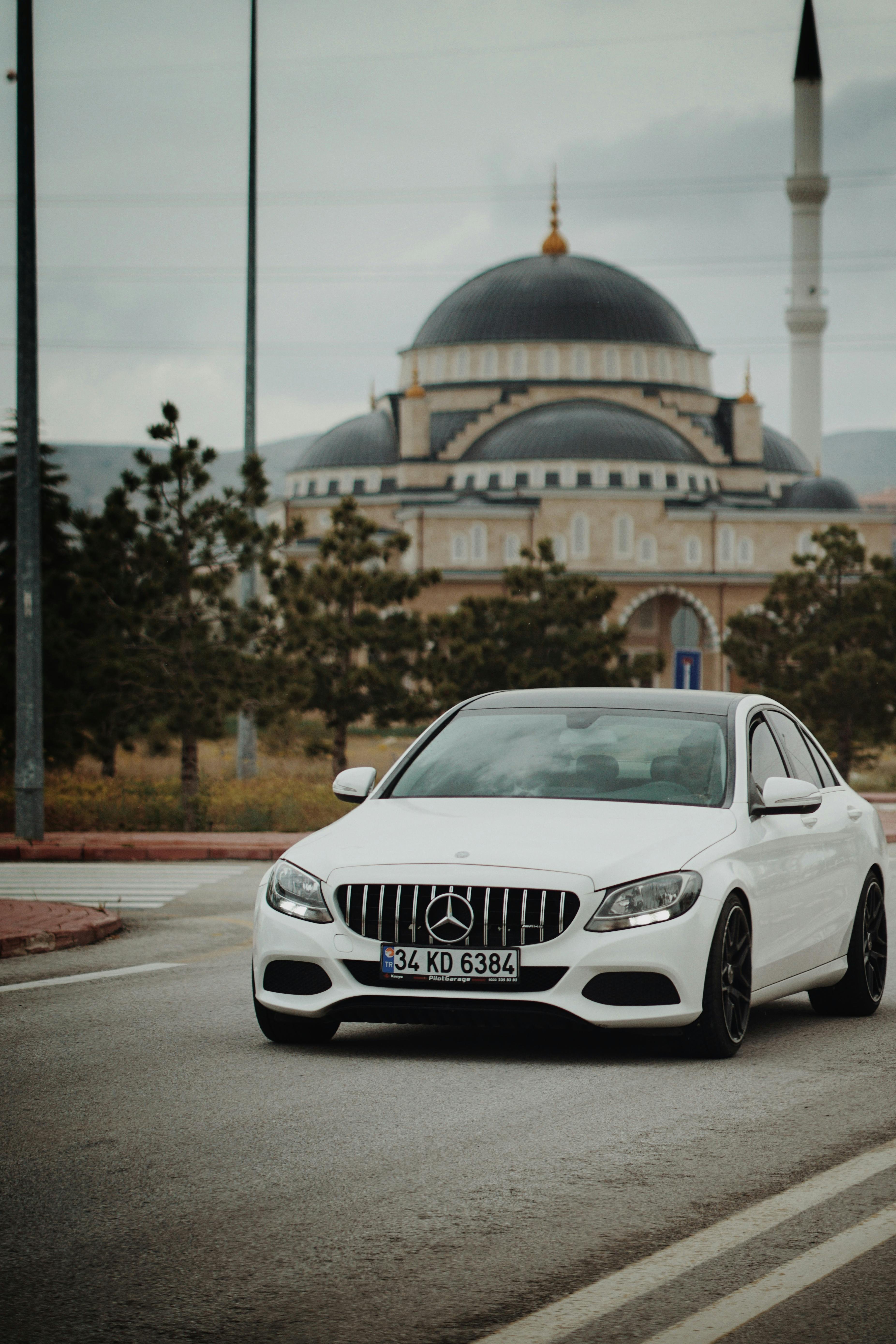 white car driving down the street from a mosque