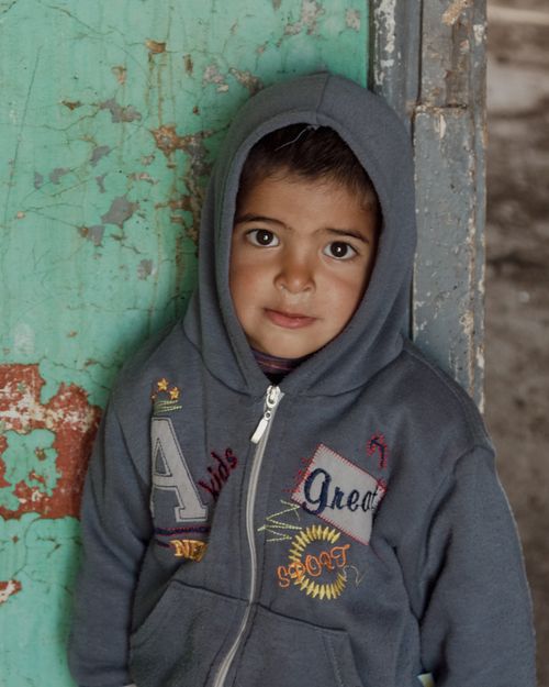 Free Portrait of a young child in a hoodie with a rustic background, capturing innocence and simplicity. Stock Photo