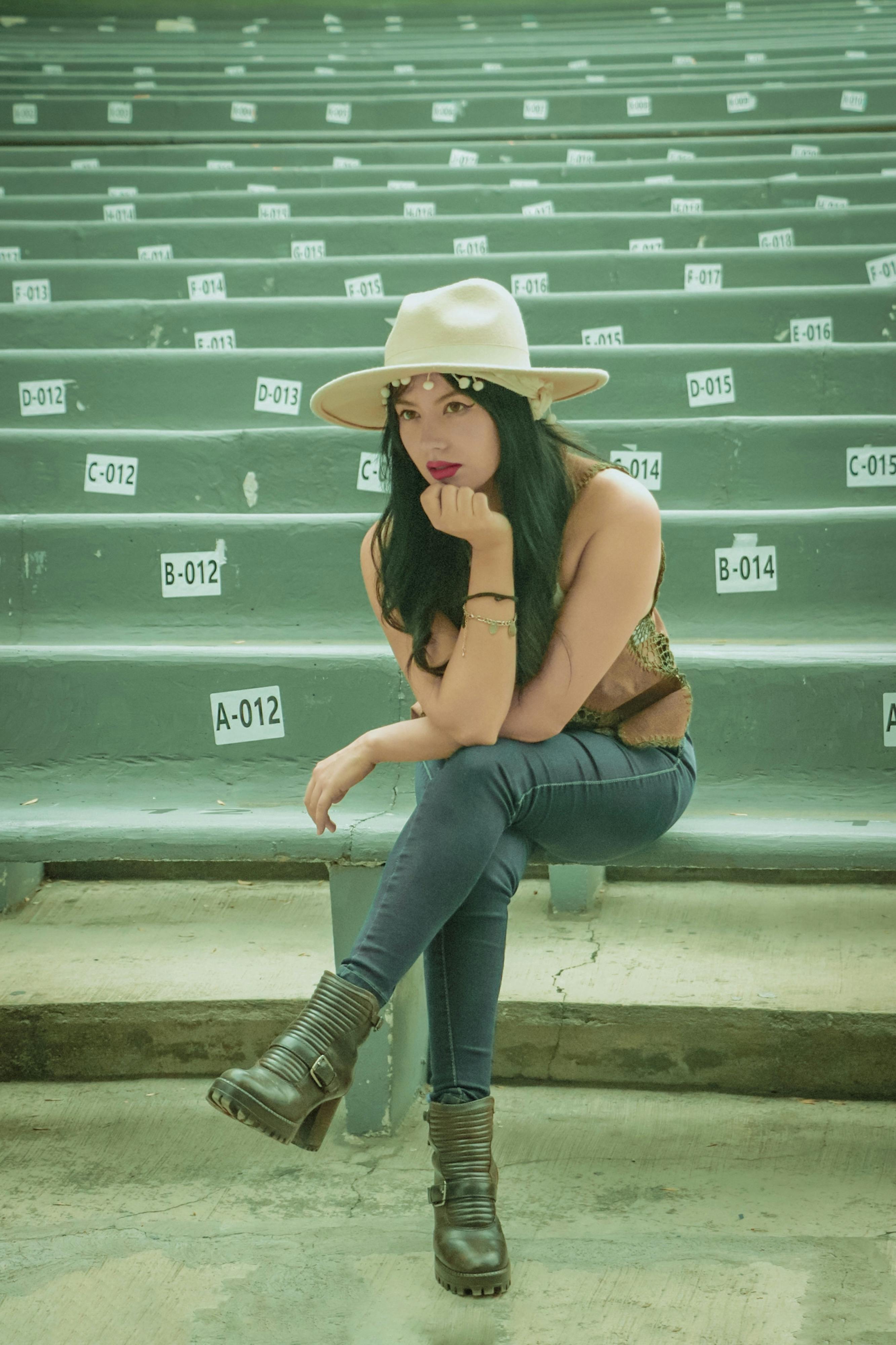 Fashionable woman posing on bench in Ciudad de México, wearing a hat and casual attire.