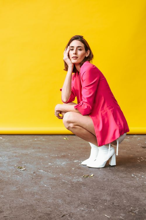 Free Fashion model in pink outfit squatting against a vibrant yellow background. Stock Photo