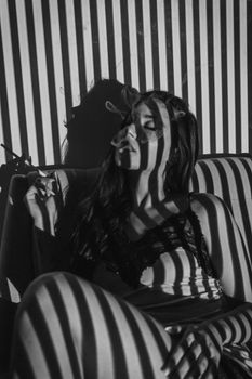 A dramatic black and white portrait of a woman, accented by striped shadows and smoke.
