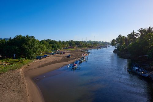 Free Aerial view of a tranquil river and boats surrounded by lush greenery under a clear blue sky. Stock Photo