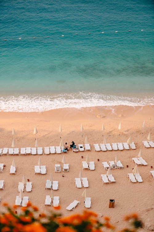 High Angle View of White Loungers on a Sandy Beach, and a Turquoise Sea