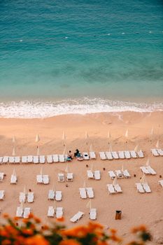 Idyllic beach scene with loungers and turquoise sea viewed from above.