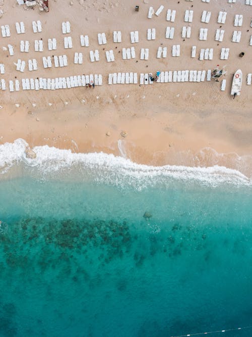 Aerial Footage of a Turquoise Sea and White Loungers on a Sandy Beach